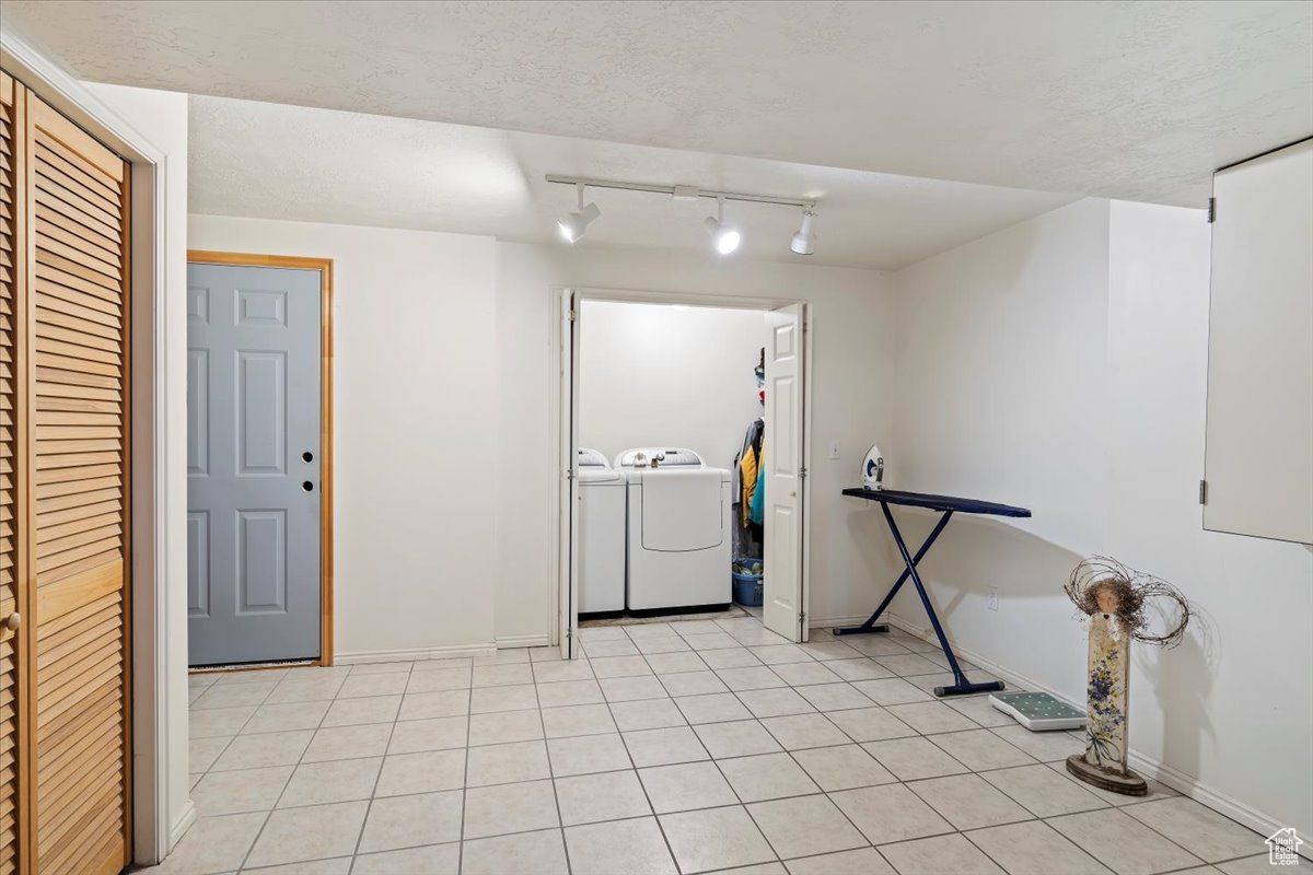 Interior space featuring track lighting, separate washer and dryer, and light tile flooring