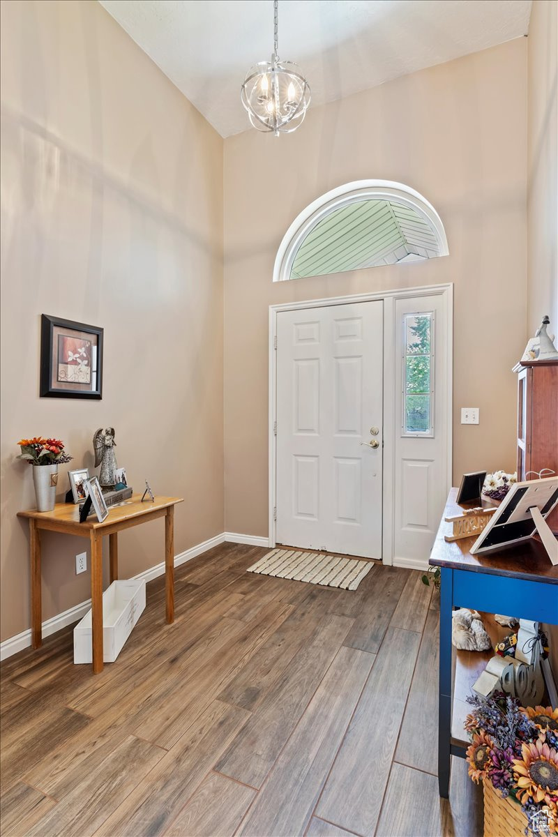 Foyer with a high ceiling, hardwood / wood-style flooring, and a chandelier