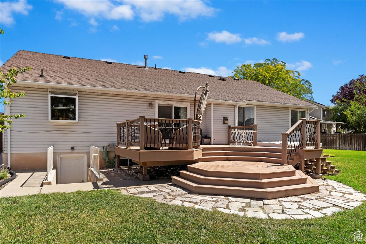 Back of property featuring a lawn and a deck