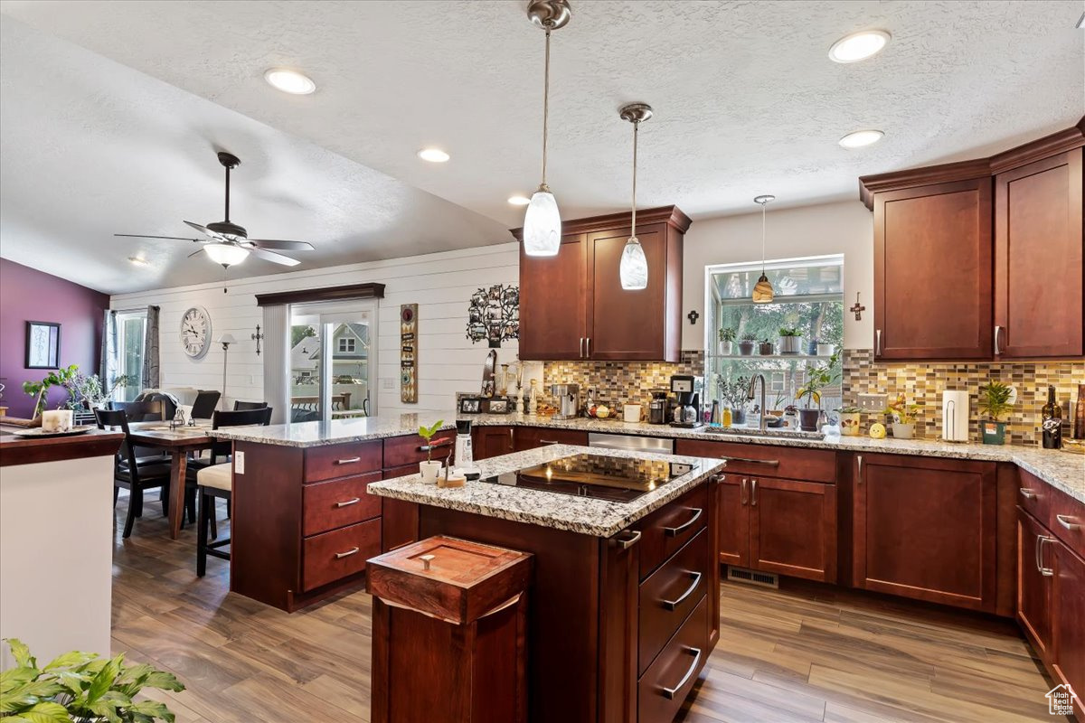 Kitchen with a wealth of natural light, vaulted ceiling, hanging light fixtures, and ceiling fan