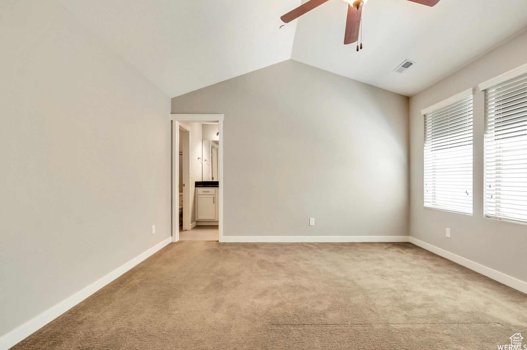 Unfurnished bedroom featuring light carpet, connected bathroom, ceiling fan, and lofted ceiling