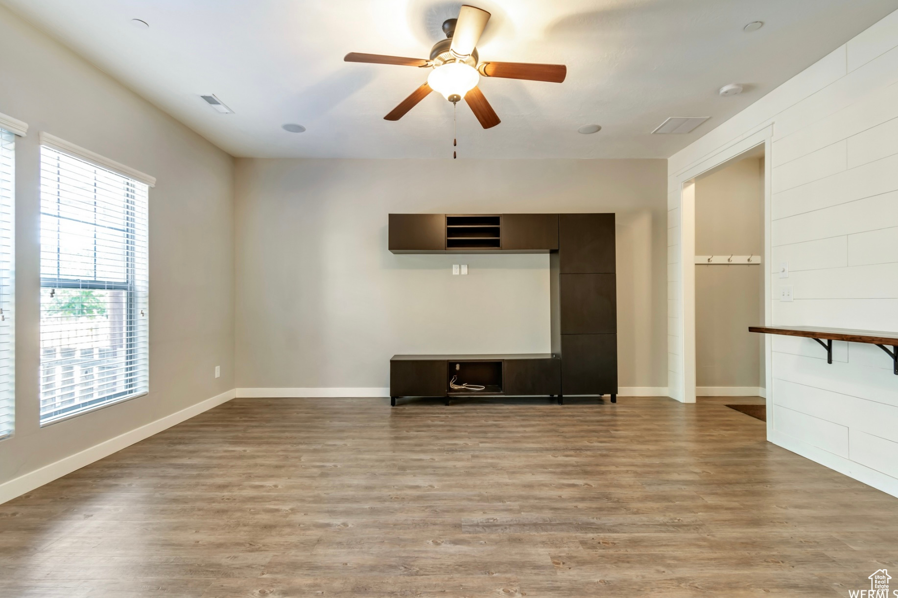 Unfurnished living room with light wood-type flooring and ceiling fan