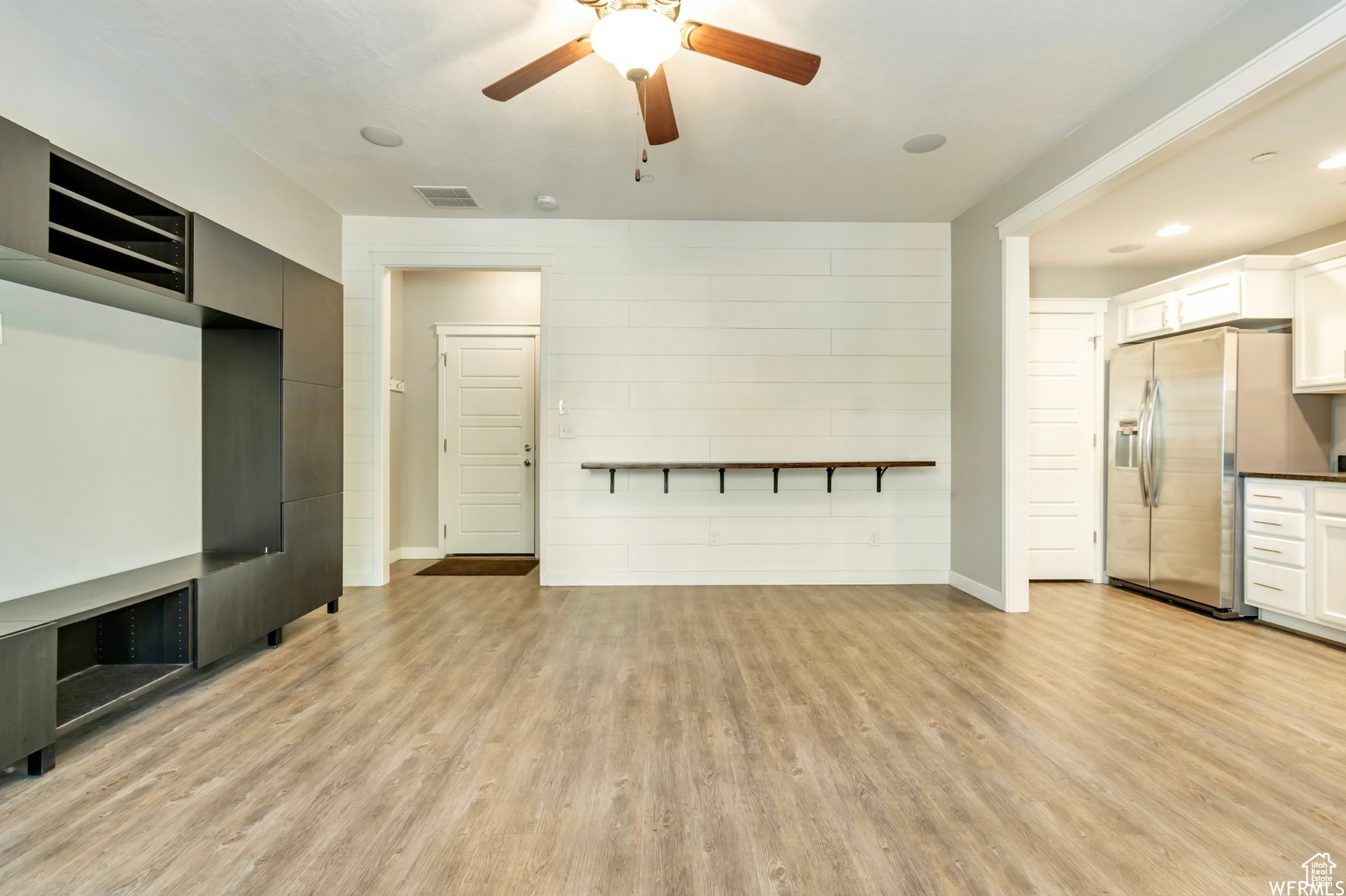 Unfurnished living room with ceiling fan and light wood-type flooring