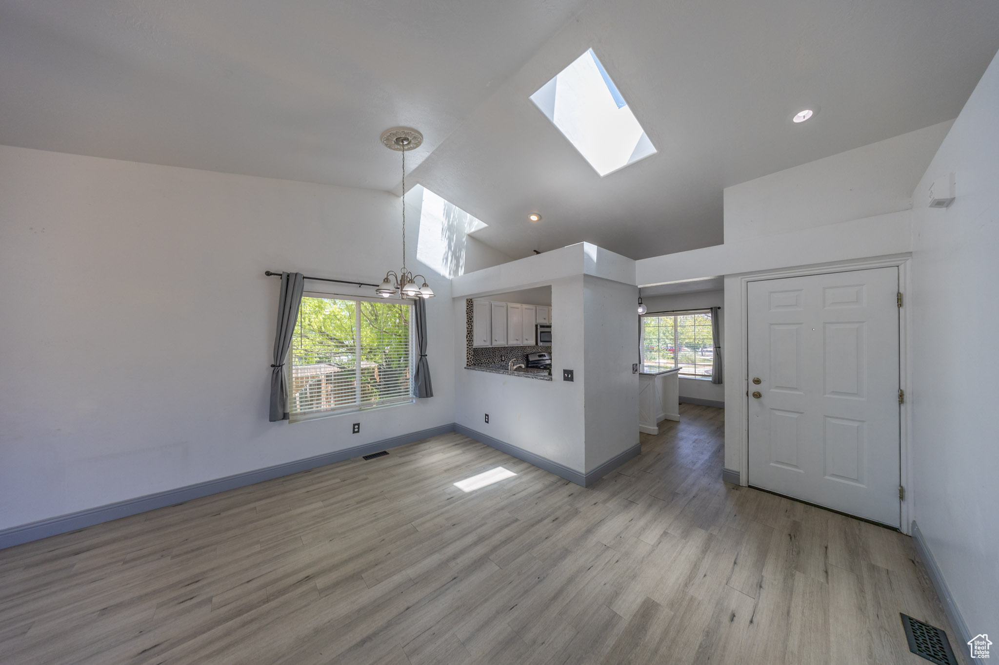 View of the front entry from main level family room, which looks into the kitchen. 2 skylights really bring in the natural light. Vaulted ceiling.