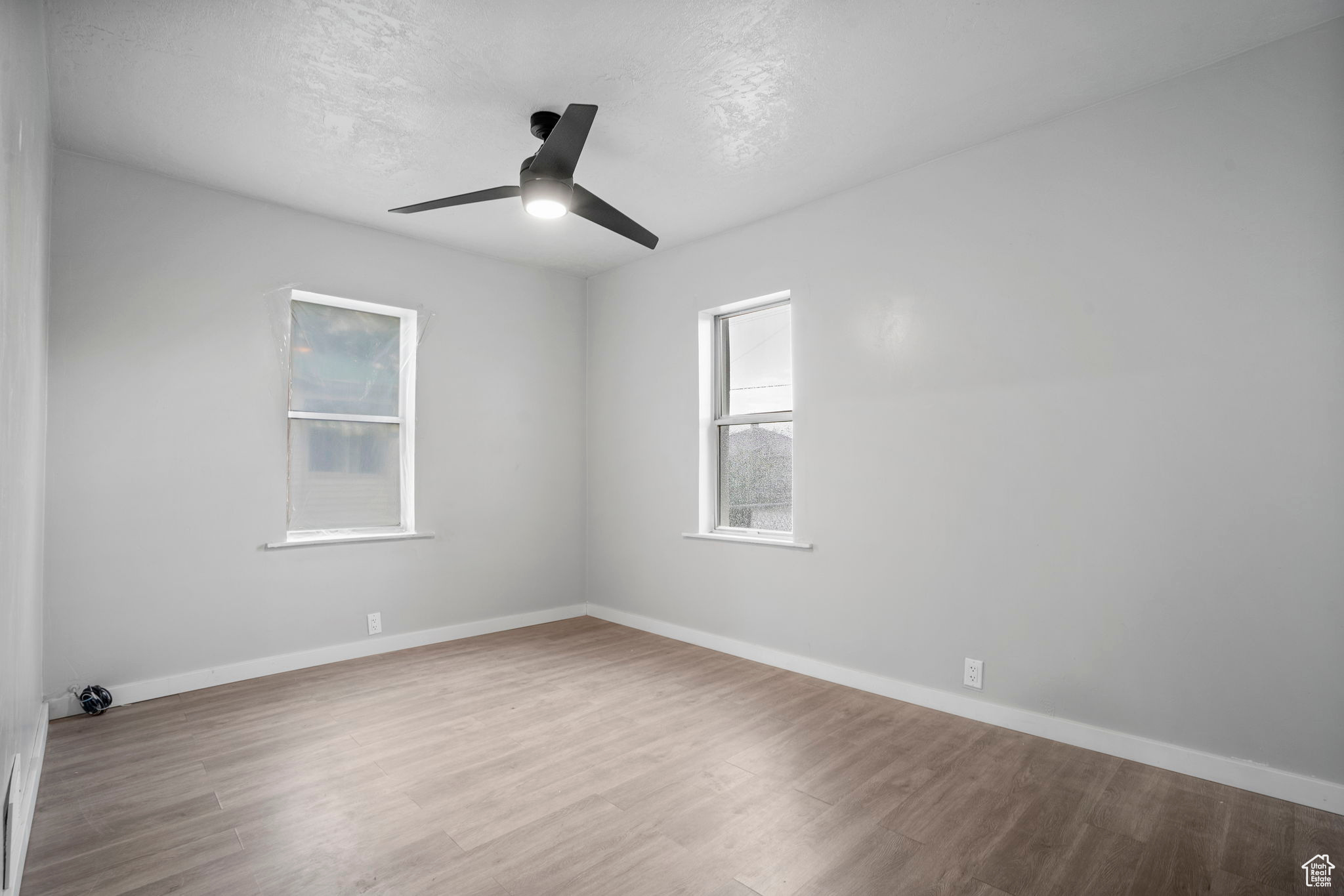 Empty room with ceiling fan and hardwood / wood-style flooring