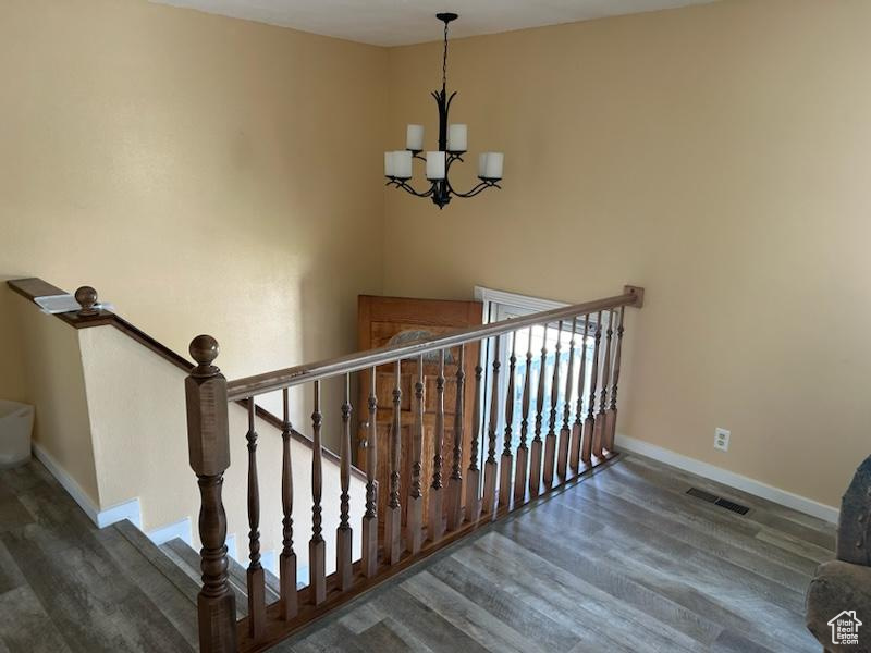 Stairs with wood-type flooring and a chandelier