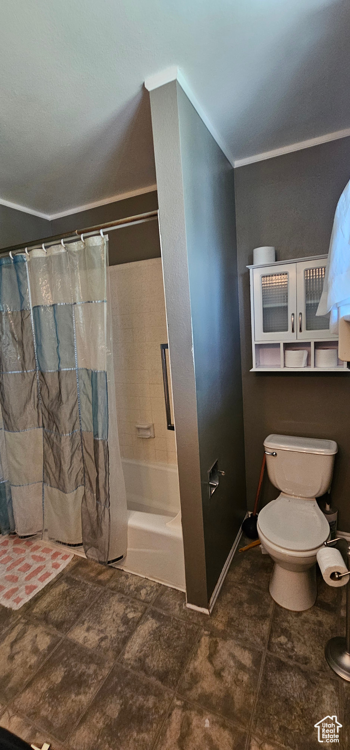 Bathroom featuring shower / bath combo with shower curtain, crown molding, toilet, and tile patterned floors