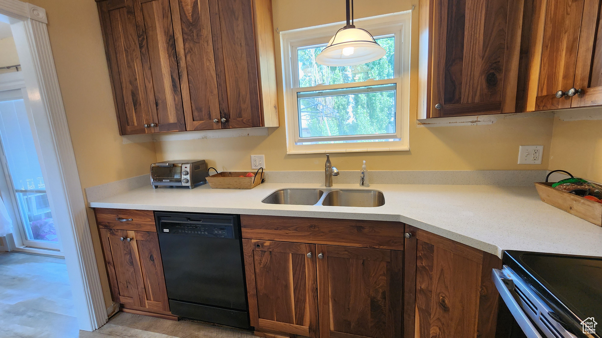 Kitchen with black dishwasher, sink, light wood-type flooring, and pendant lighting