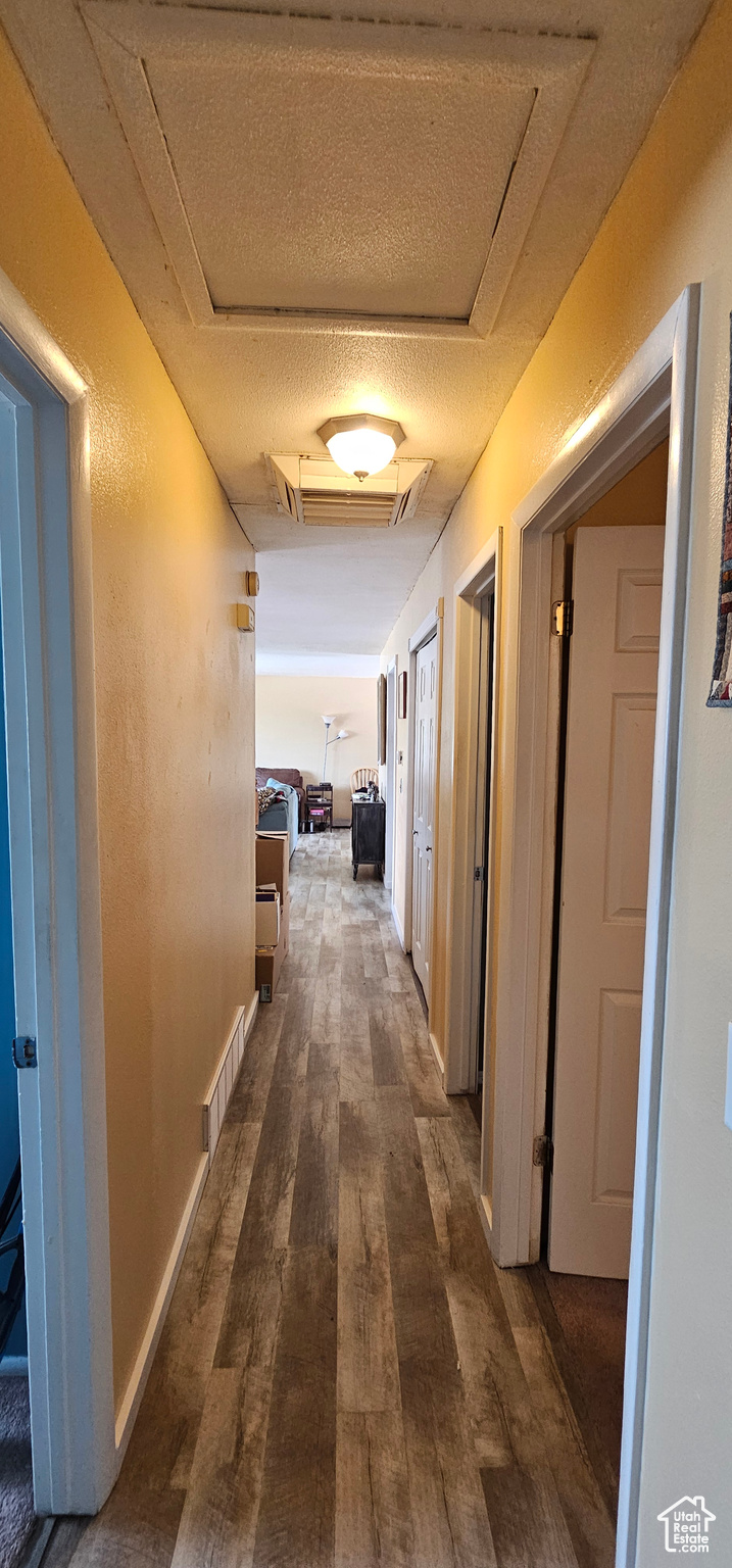 Corridor with a textured ceiling and dark hardwood / wood-style floors