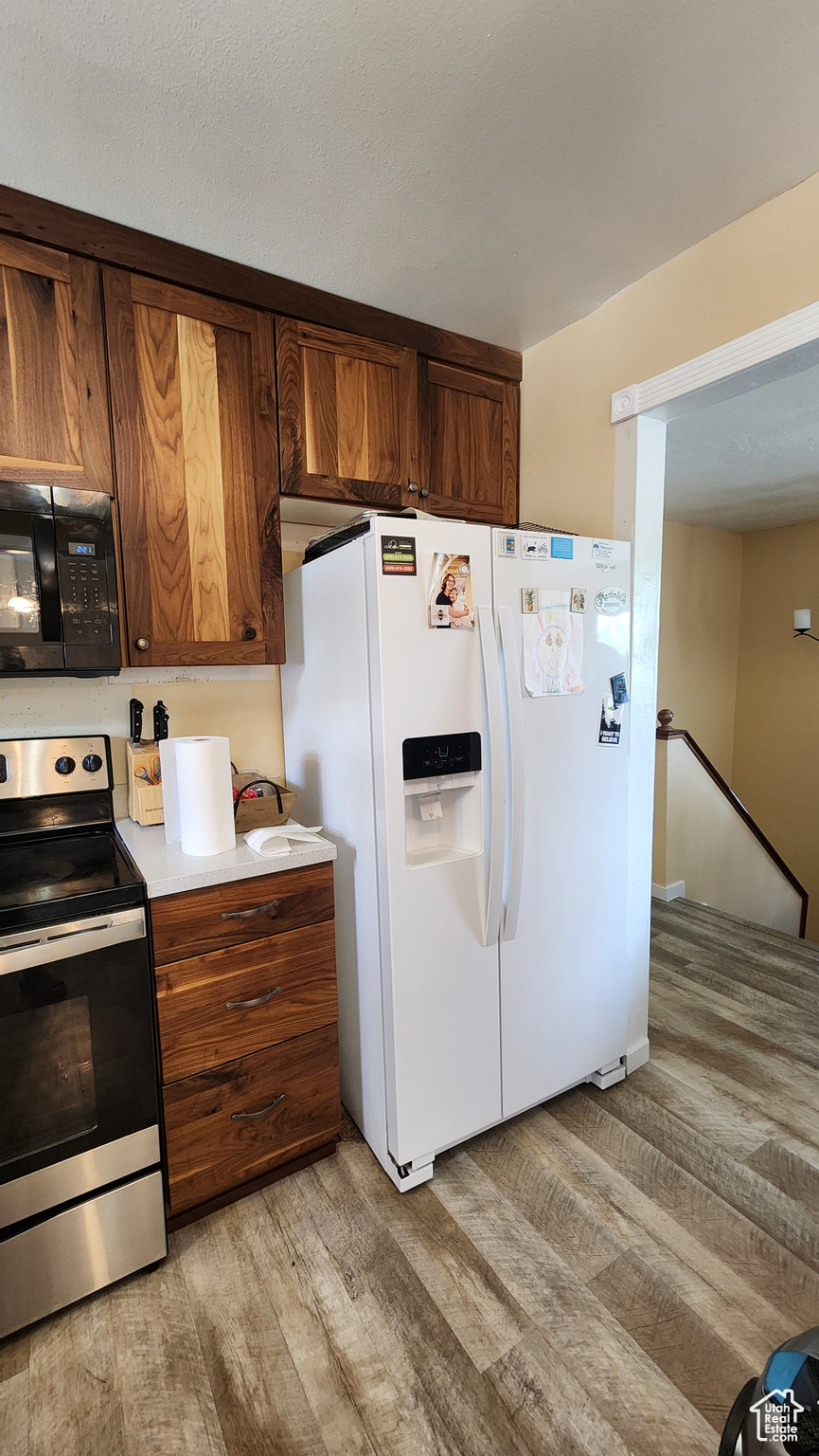 Kitchen featuring stainless steel electric range, hardwood / wood-style floors, and white fridge with ice dispenser