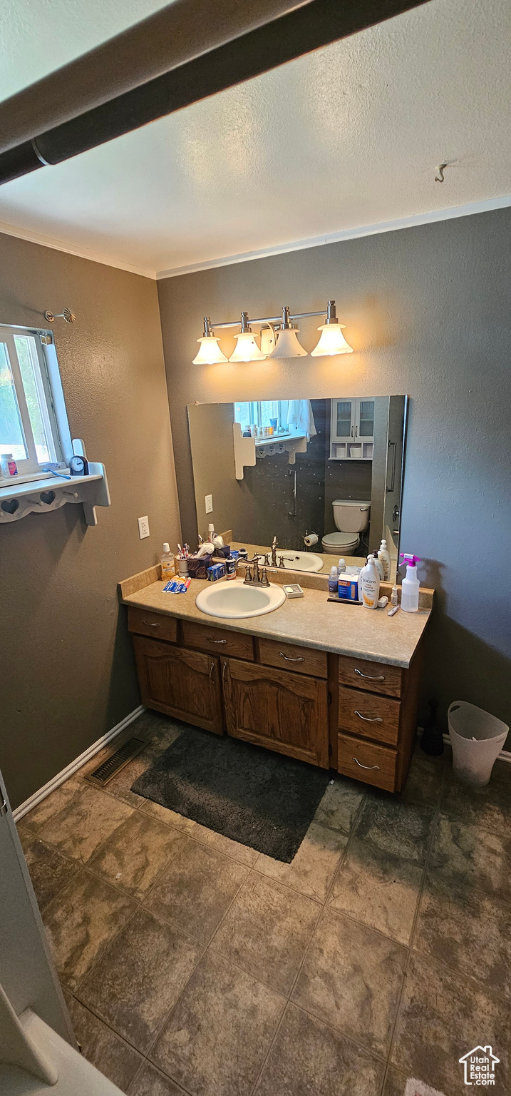 Bathroom featuring vanity, tile patterned floors, ornamental molding, toilet, and a textured ceiling