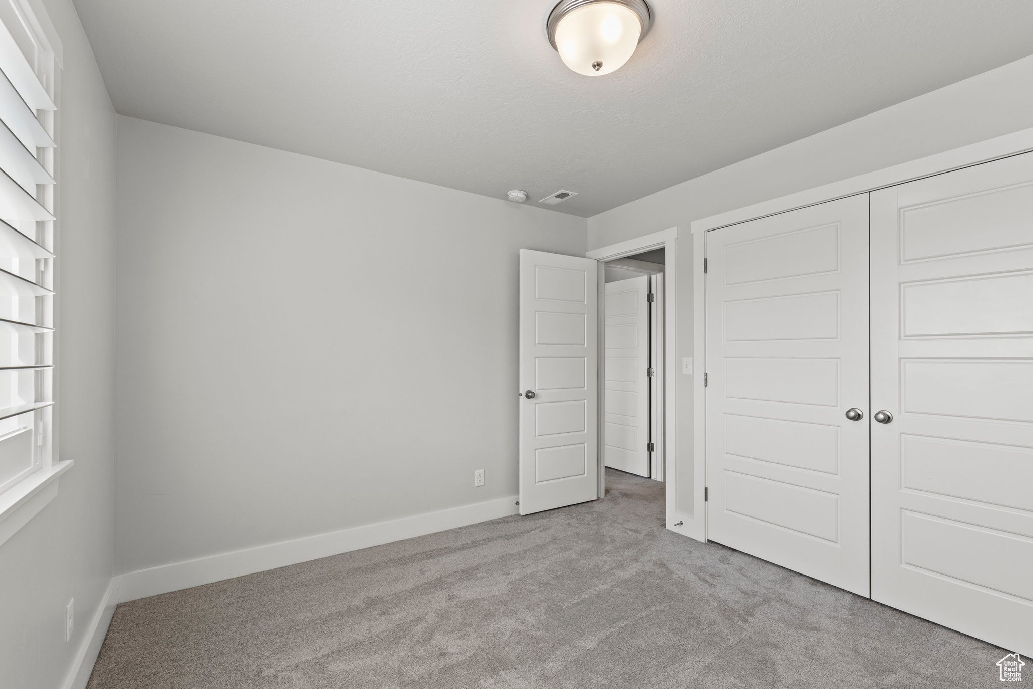 Unfurnished bedroom featuring light colored carpet and a closet