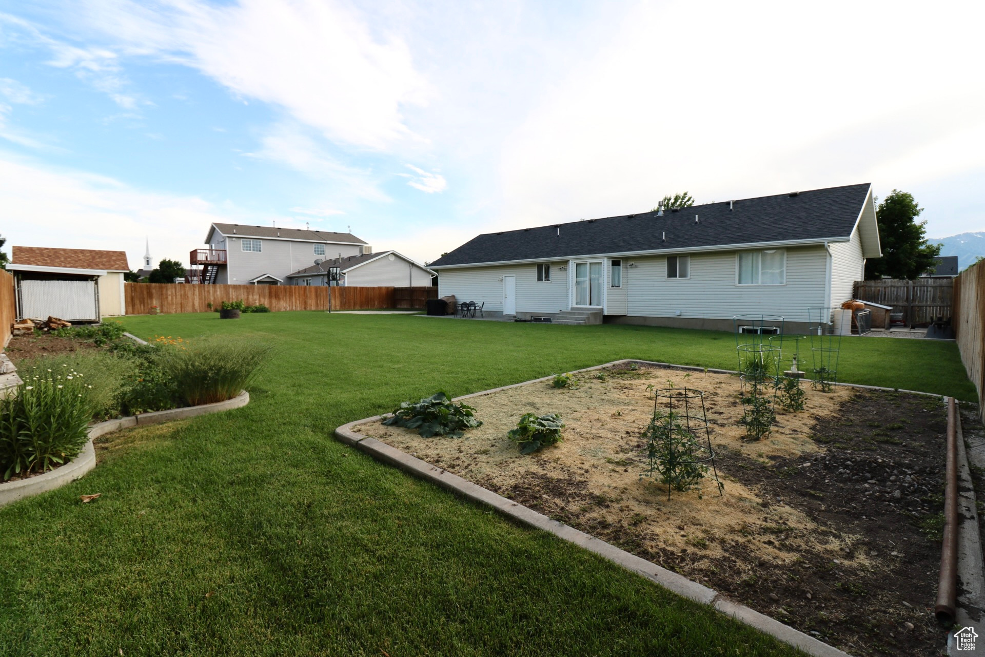 Rear view of house featuring an outdoor structure and a lawn