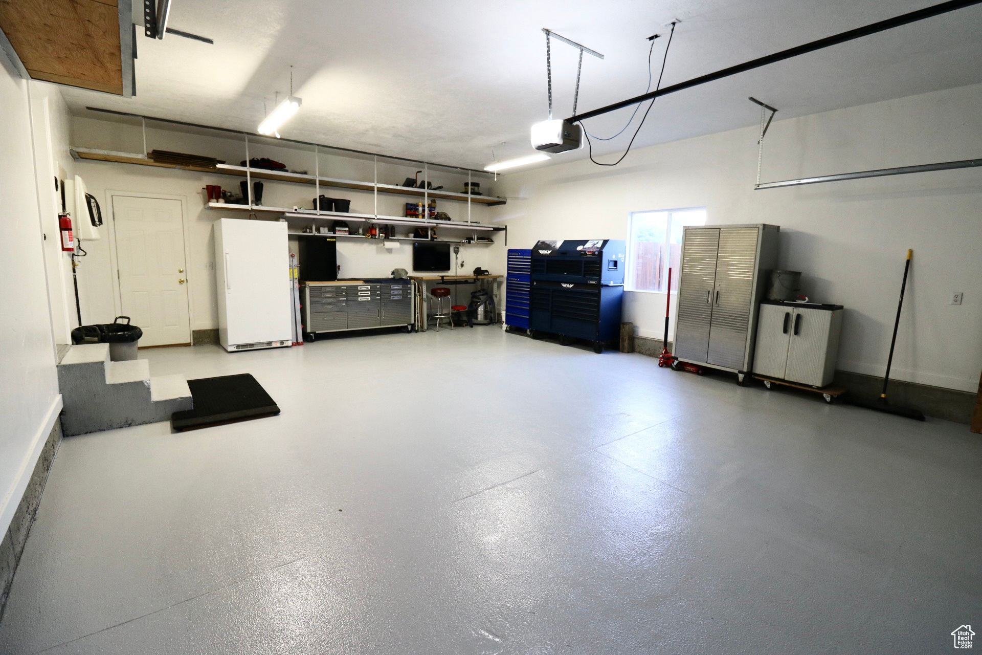 Garage with a garage door opener and white fridge