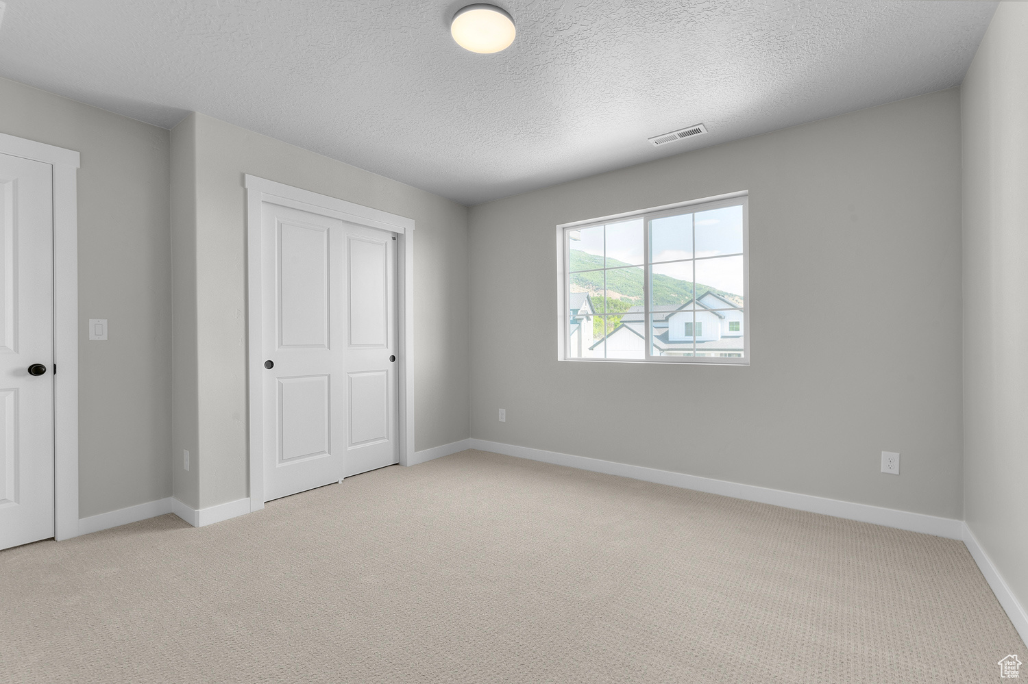 Unfurnished bedroom with light carpet and a textured ceiling