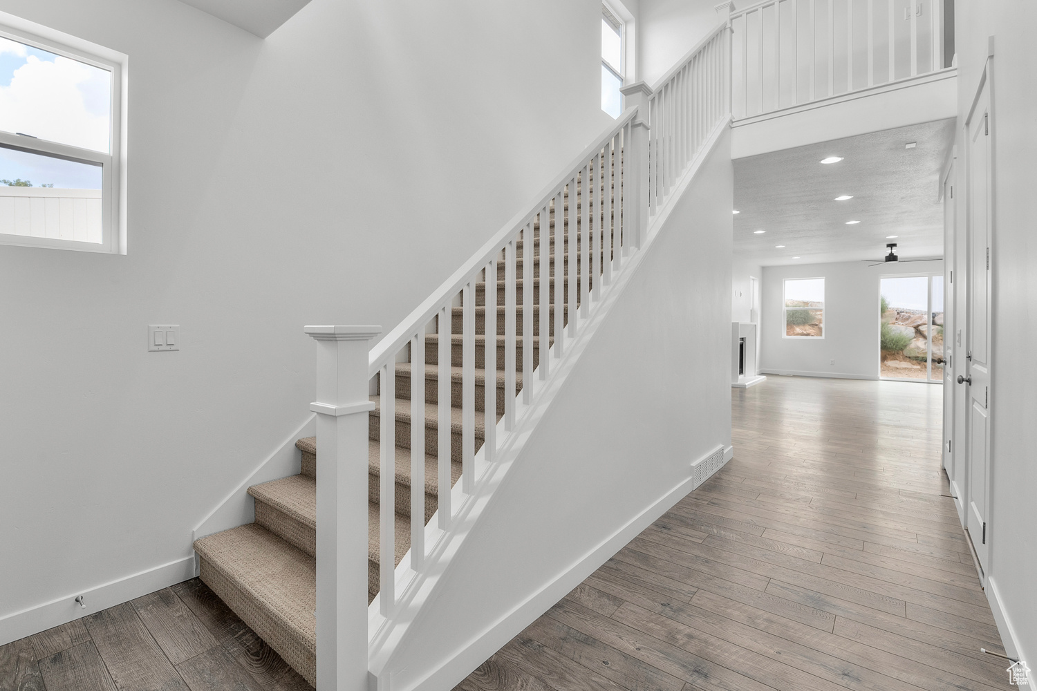 Stairway with hardwood / wood-style floors and a towering ceiling