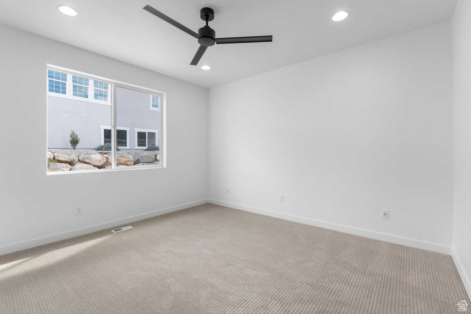 Carpeted empty room featuring ceiling fan