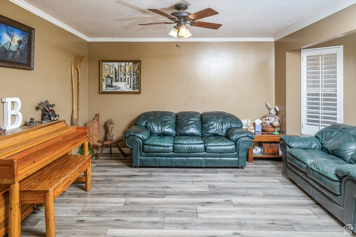 Living room with ceiling fan, crown molding, and wood-type flooring