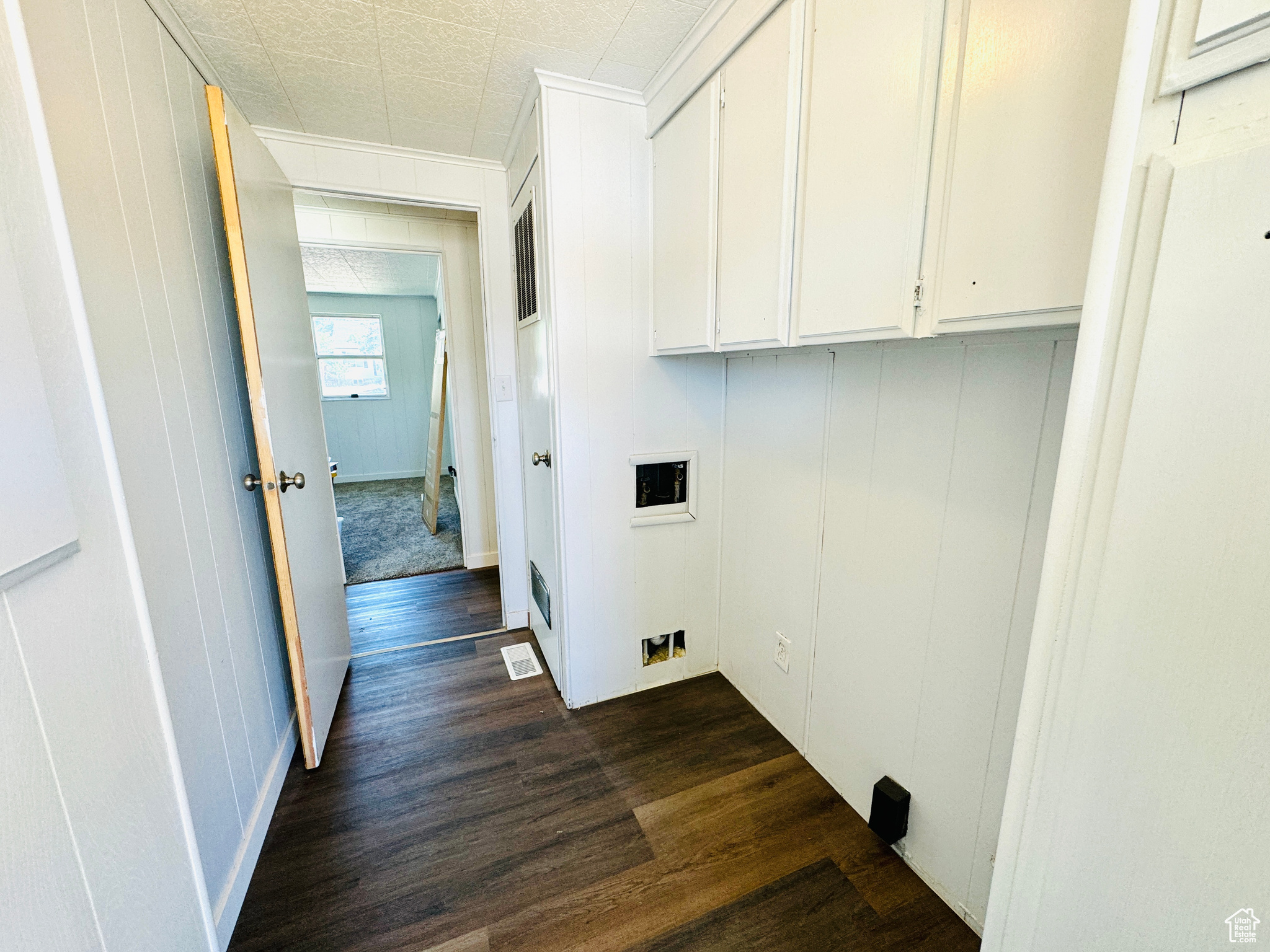 Laundry room with dark wood-type flooring, cabinets, and washer hookup