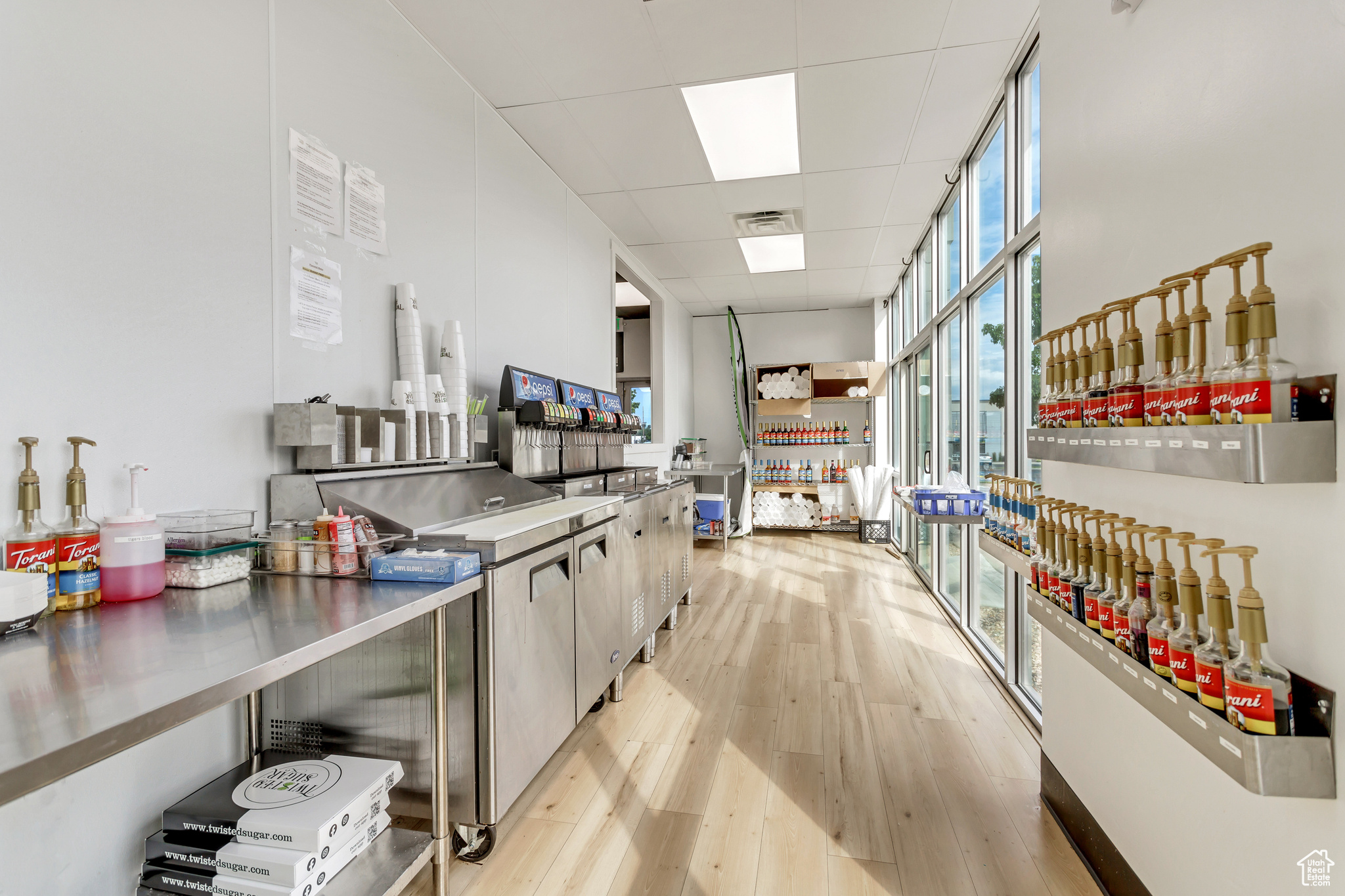 Kitchen featuring stainless steel counters, a drop ceiling, plenty of natural light, and light hardwood / wood-style flooring