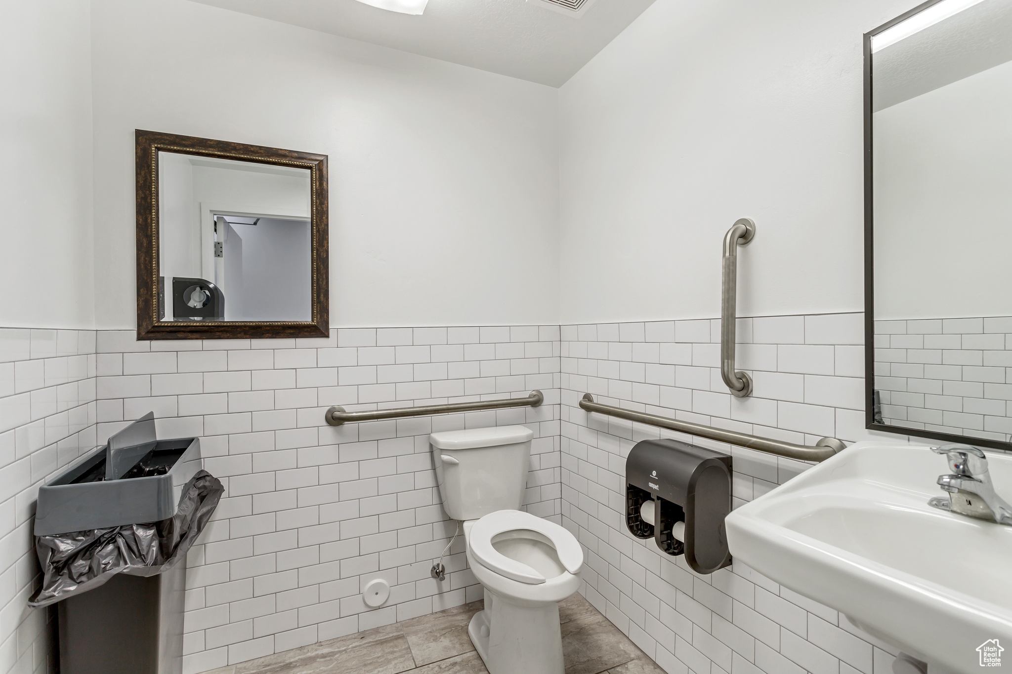 Bathroom with tile walls, tile flooring, and toilet