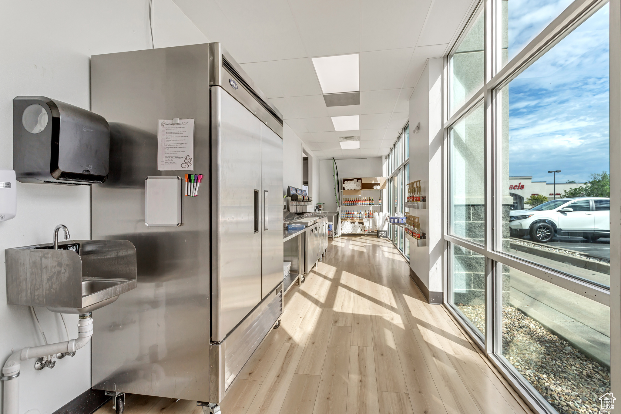 Kitchen with high end fridge, plenty of natural light, light wood-type flooring, and a drop ceiling