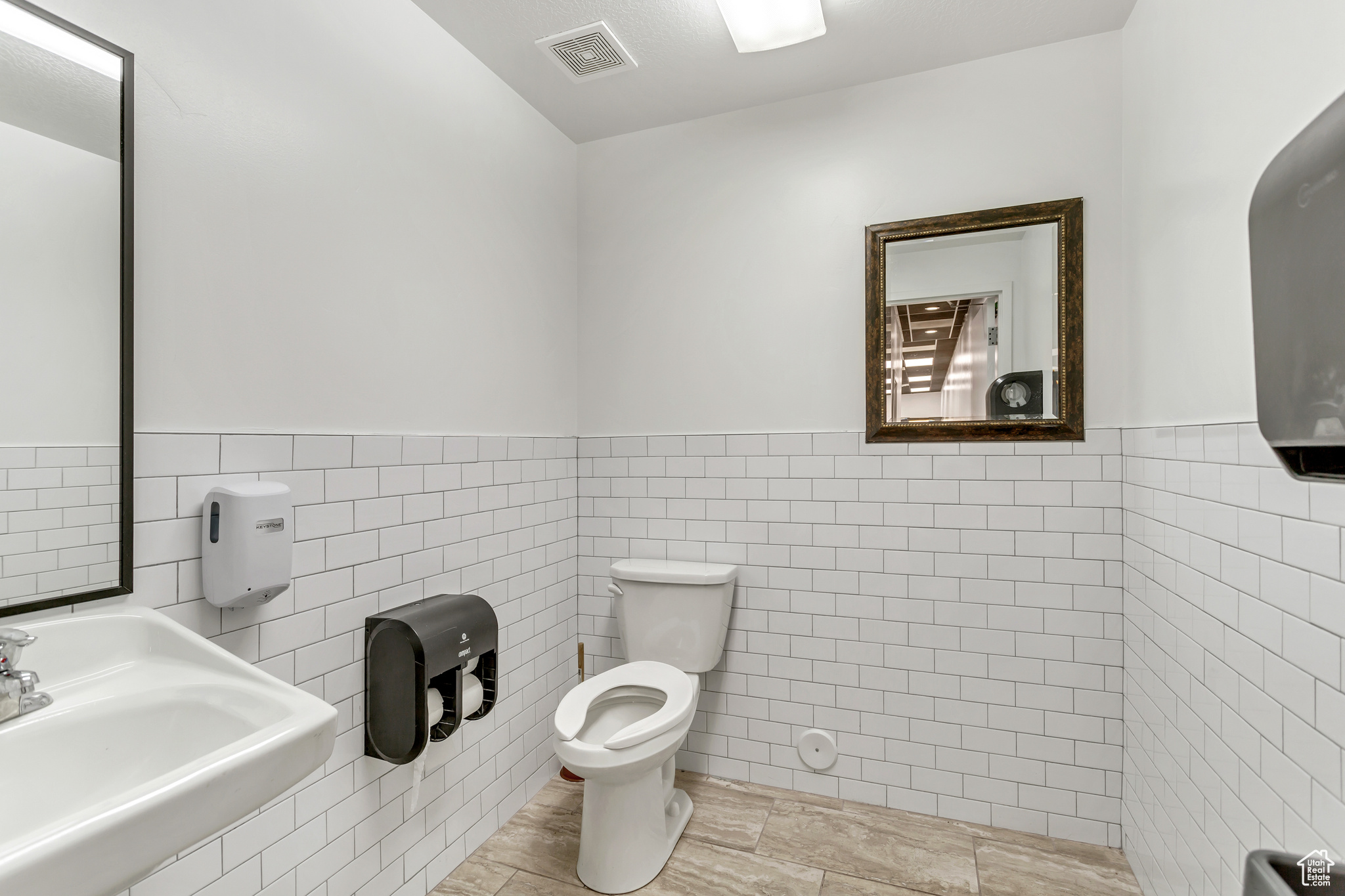 Bathroom featuring sink, tile flooring, toilet, and tile walls