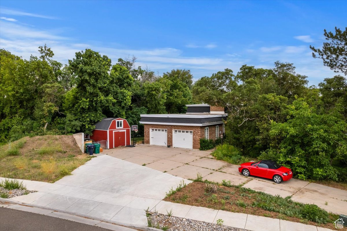 View of front of home featuring a garage and a shed