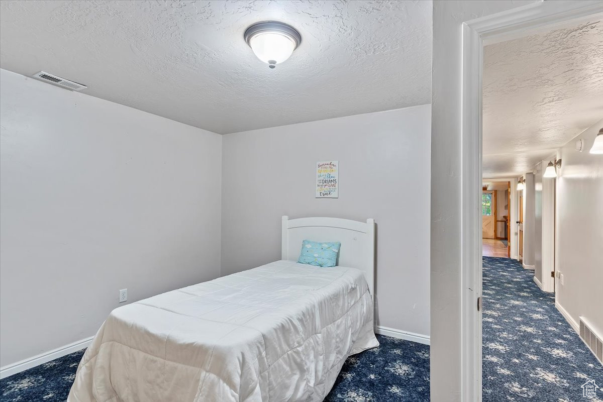 Bedroom with dark colored carpet and a textured ceiling