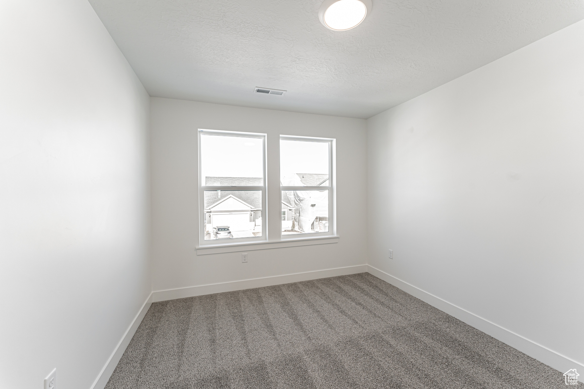 Carpeted spare room featuring a textured ceiling