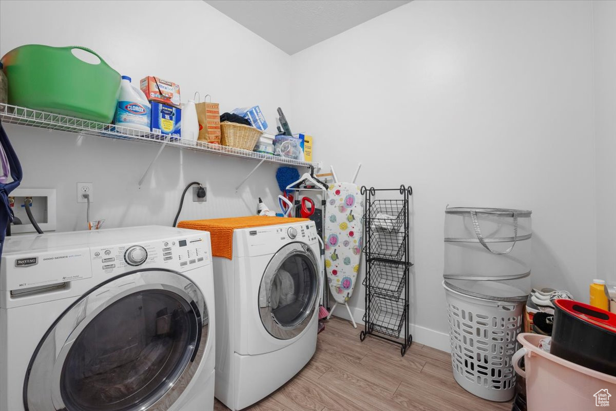 Laundry room with independent washer and dryer and light hardwood / wood-style floors
