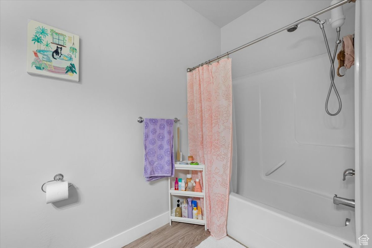 Bathroom featuring shower / bathtub combination with curtain and hardwood / wood-style flooring