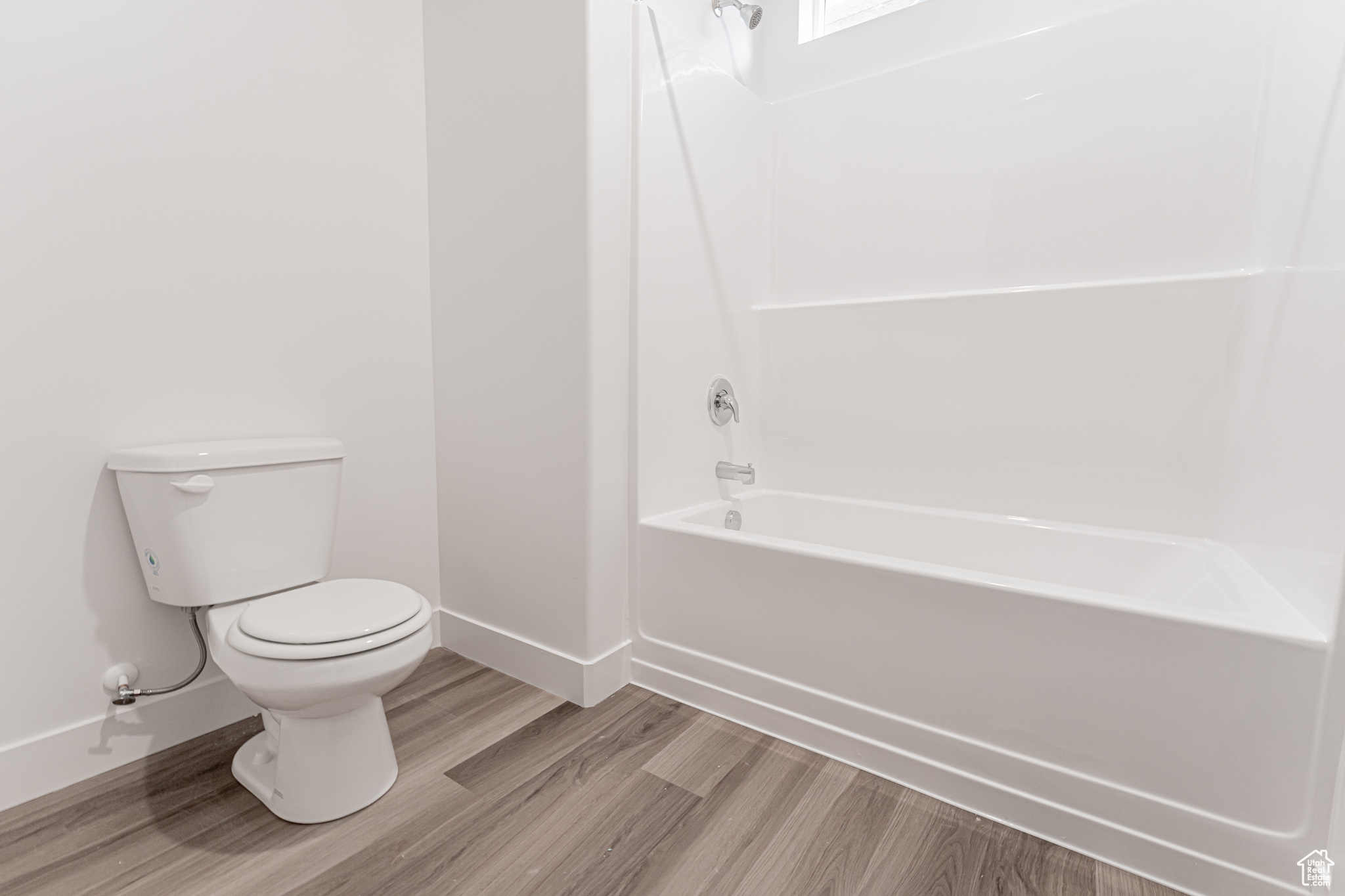 Bathroom featuring hardwood / wood-style flooring, toilet, and shower / washtub combination