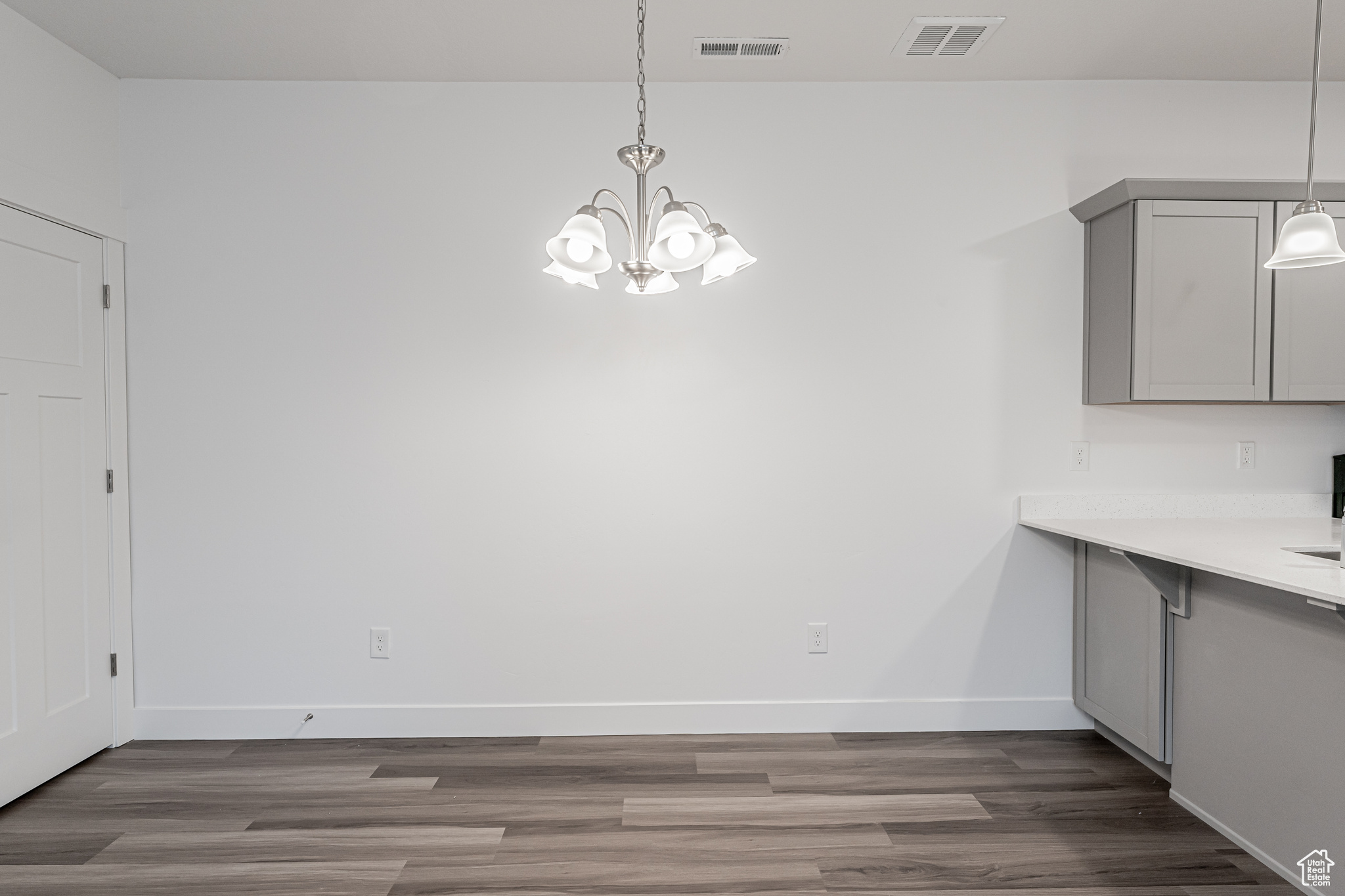 Unfurnished dining area featuring dark wood-type flooring and a chandelier