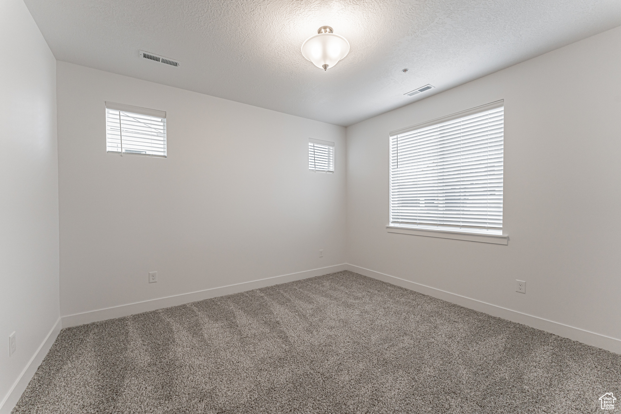 Empty room with a textured ceiling and carpet floors