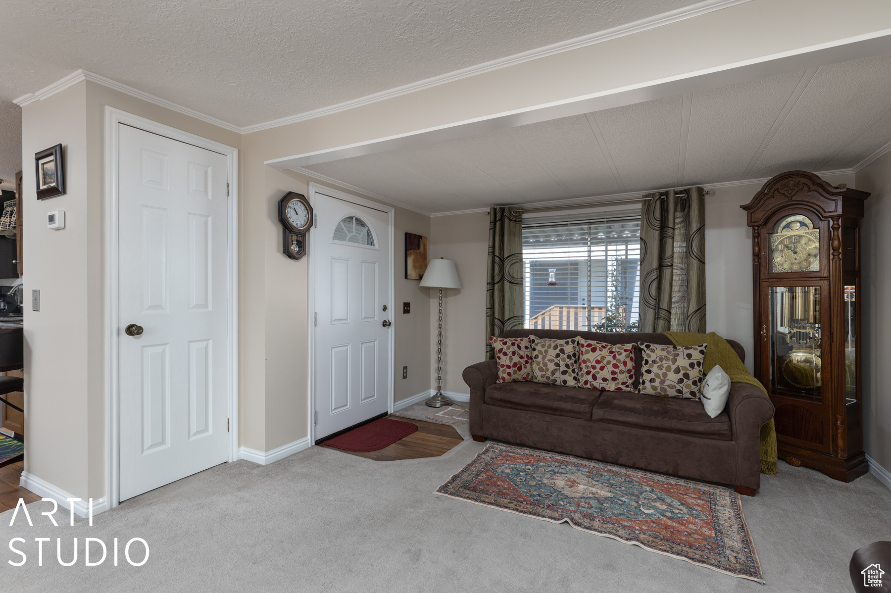 Carpeted living room featuring crown molding and a textured ceiling