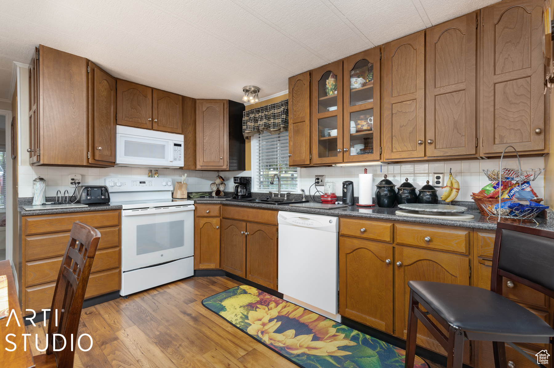 Kitchen with hardwood / wood-style flooring, backsplash, white appliances, and sink