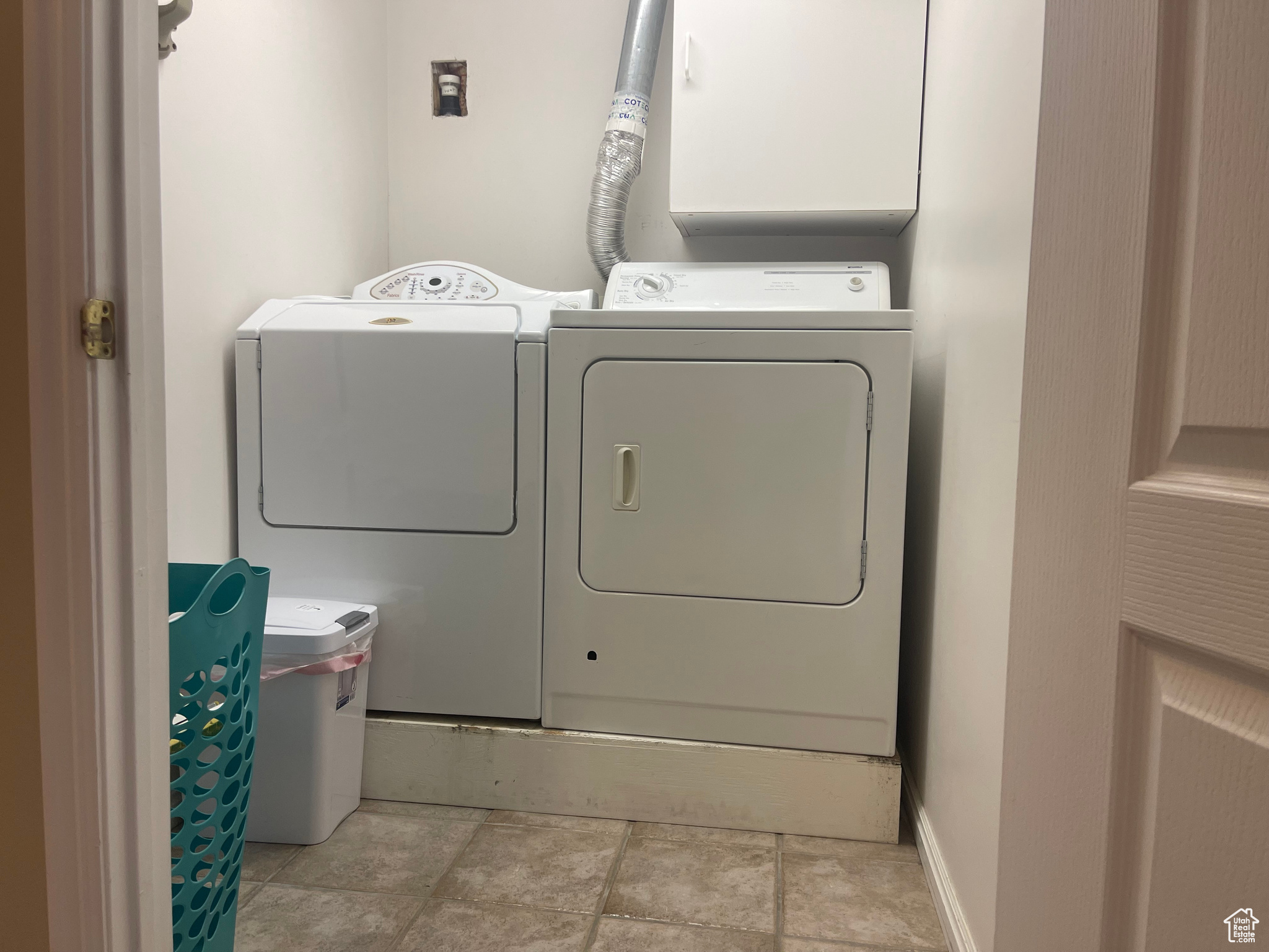 Laundry with washing machine and dryer and light tile patterned floors