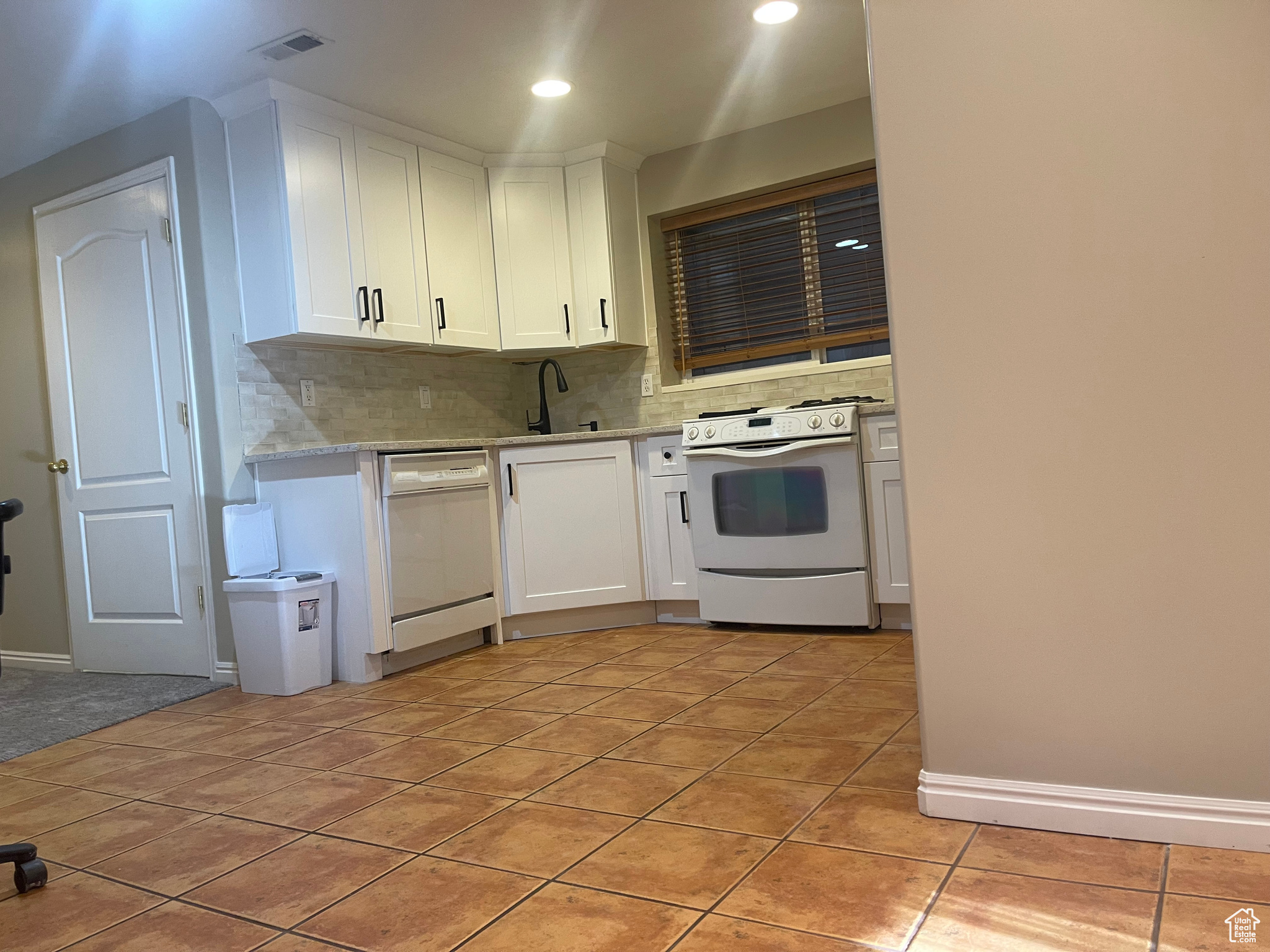 Kitchen featuring light tile patterned flooring, white cabinets, white appliances, sink, and light stone countertops