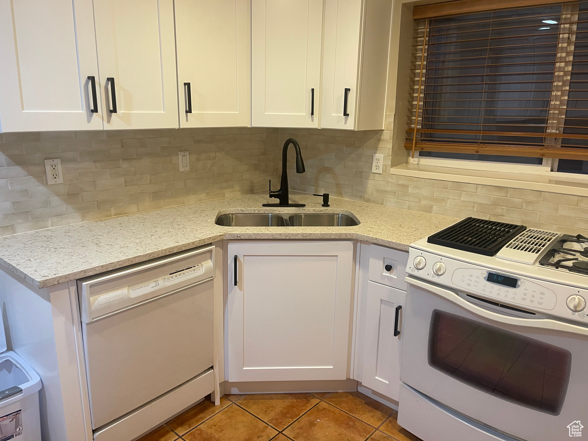 Kitchen with white cabinetry, tasteful backsplash, white appliances, and sink