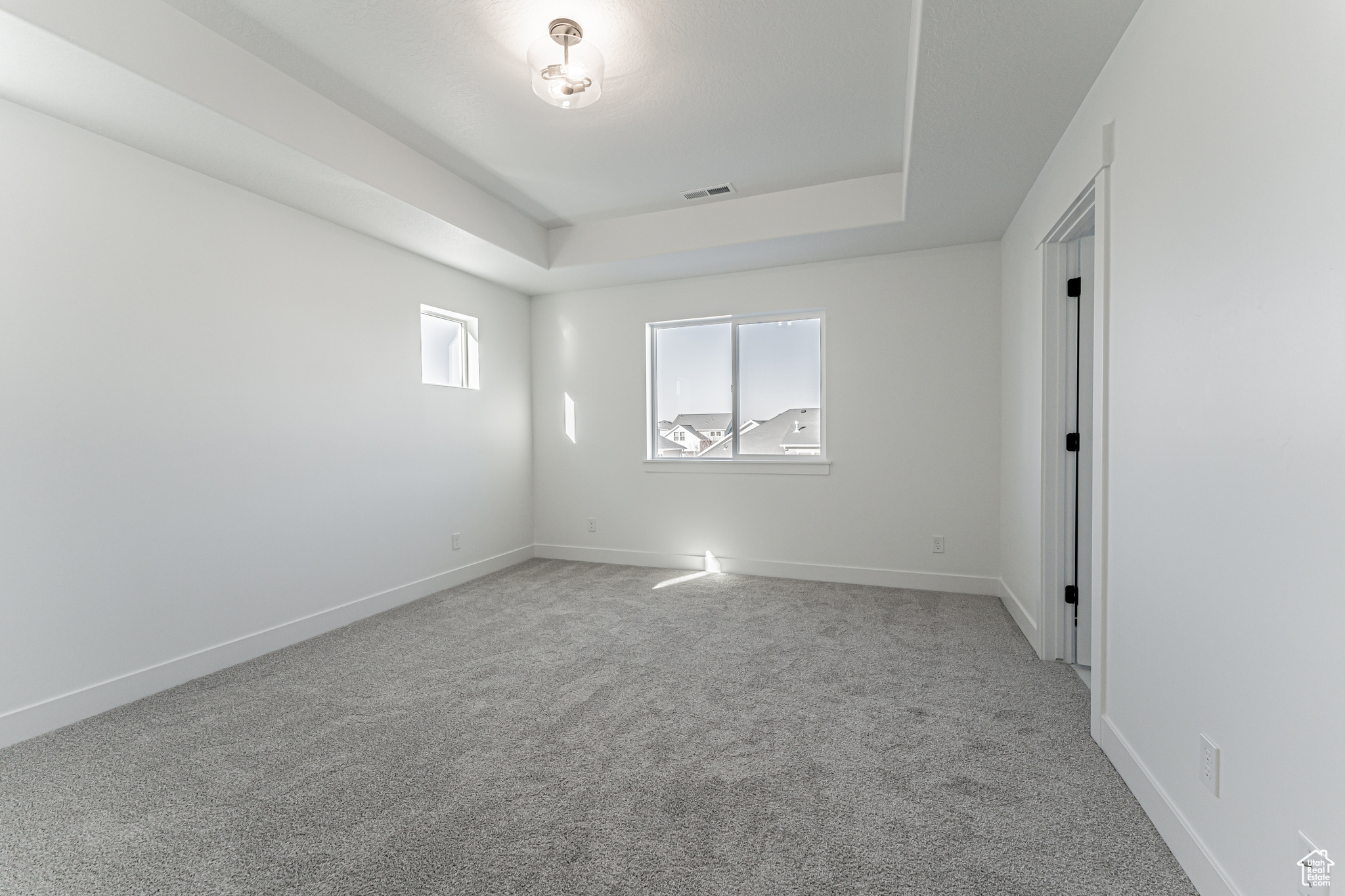 Spare room featuring a tray ceiling and carpet flooring