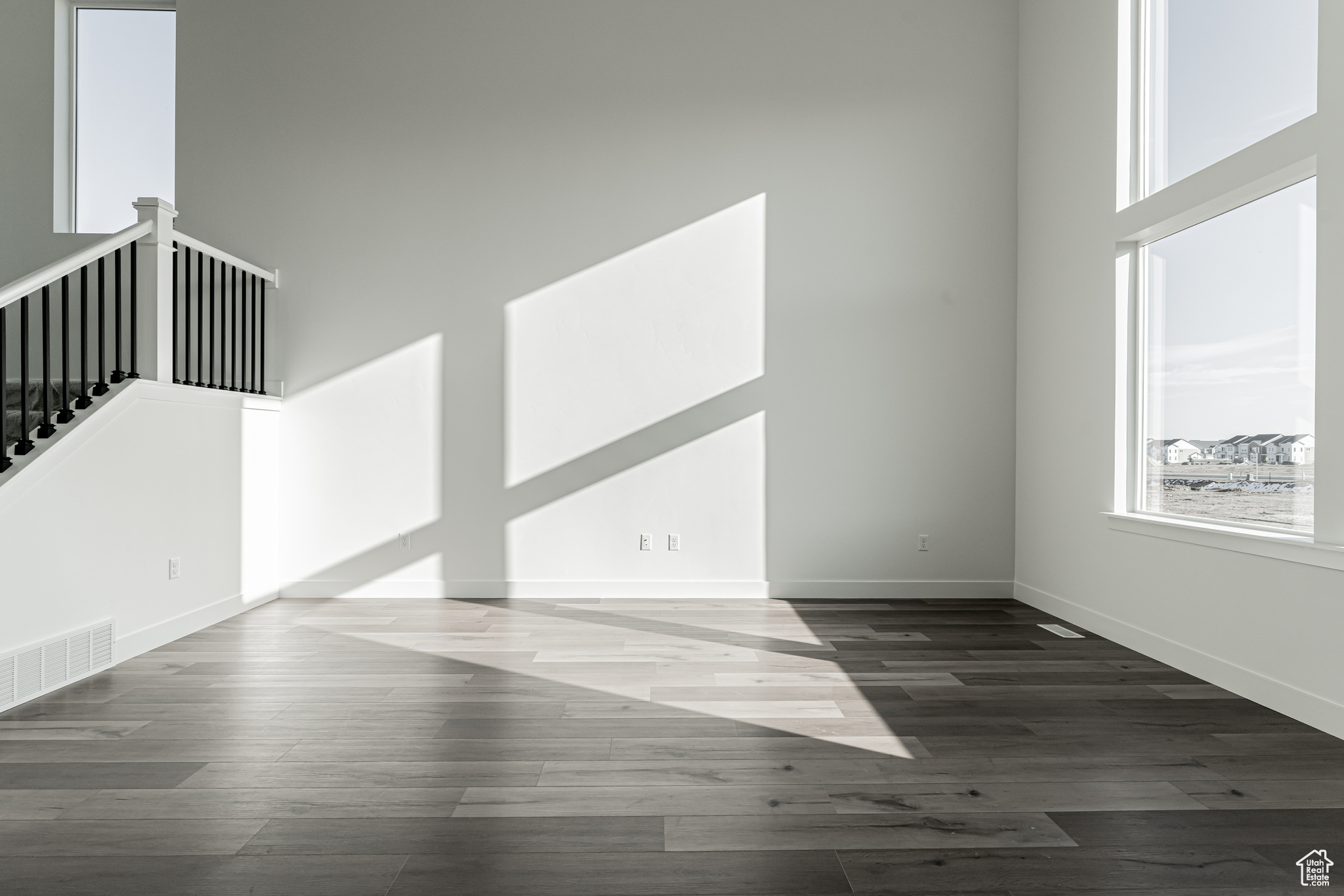 Unfurnished room with dark hardwood / wood-style flooring and a towering ceiling