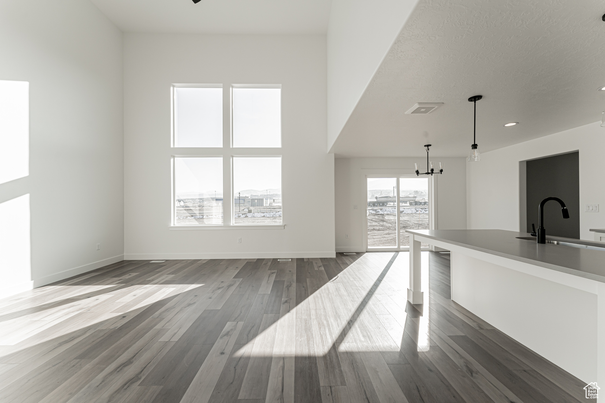 Unfurnished living room featuring an inviting chandelier, wood-type flooring, and sink