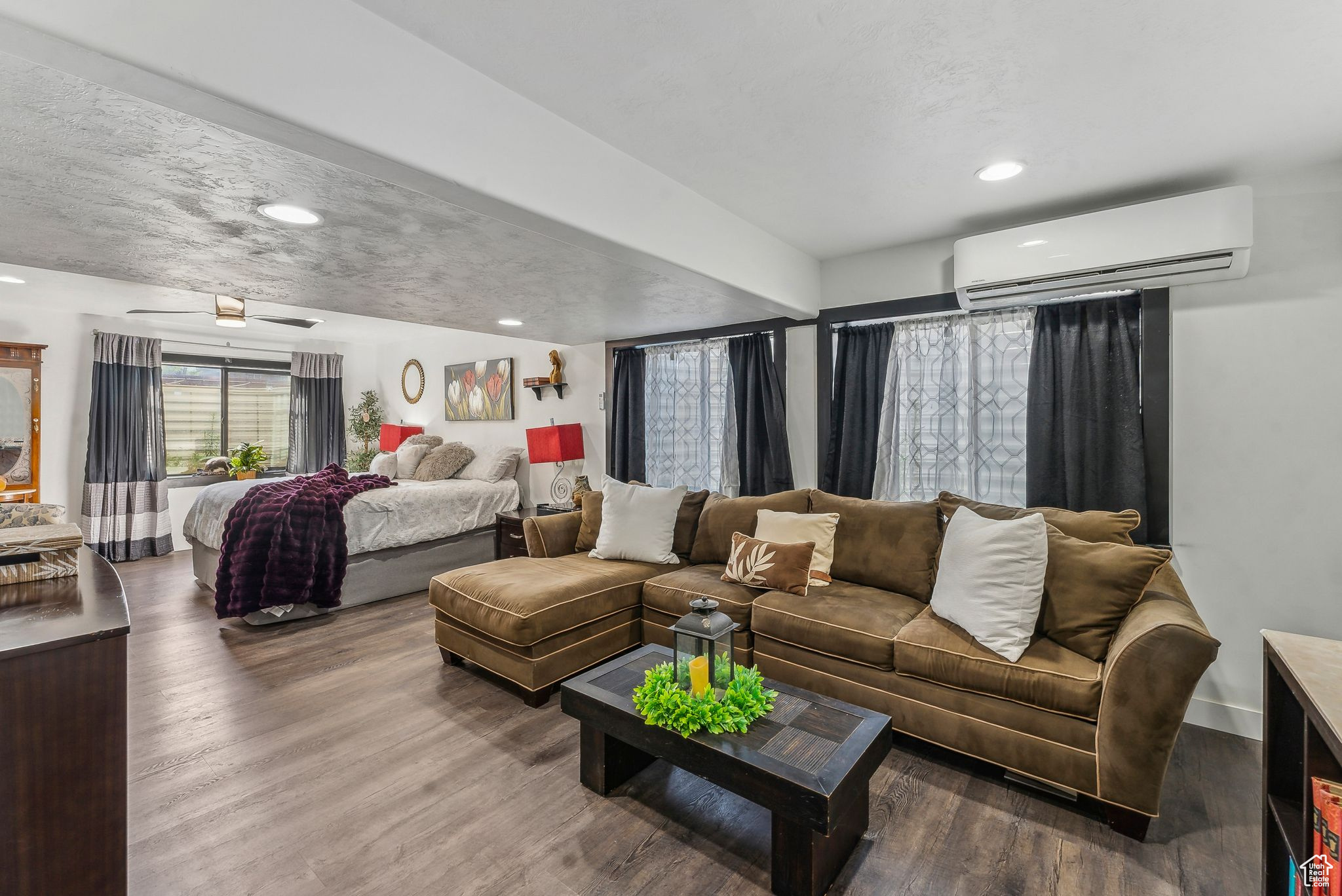 Living room featuring a wall mounted air conditioner, a textured ceiling, ceiling fan, and wood-type flooring