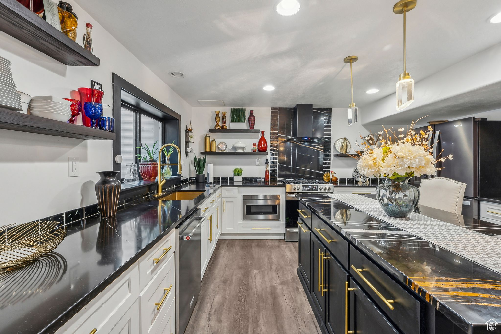 Kitchen featuring stainless steel appliances, white cabinets, sink, hanging light fixtures, and dark hardwood / wood-style floors