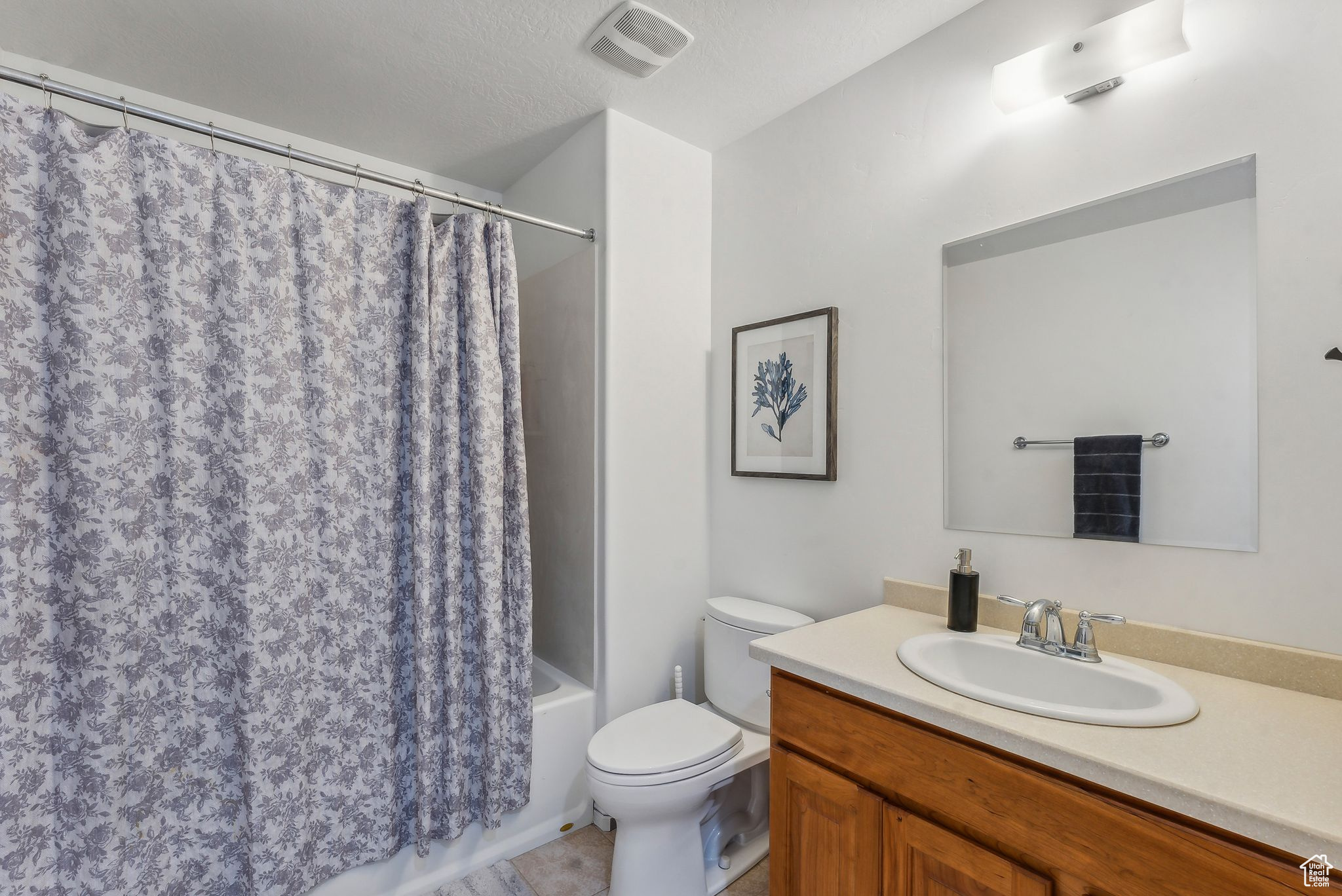 Full bathroom featuring vanity, shower / bathtub combination with curtain, toilet, a textured ceiling, and tile patterned flooring