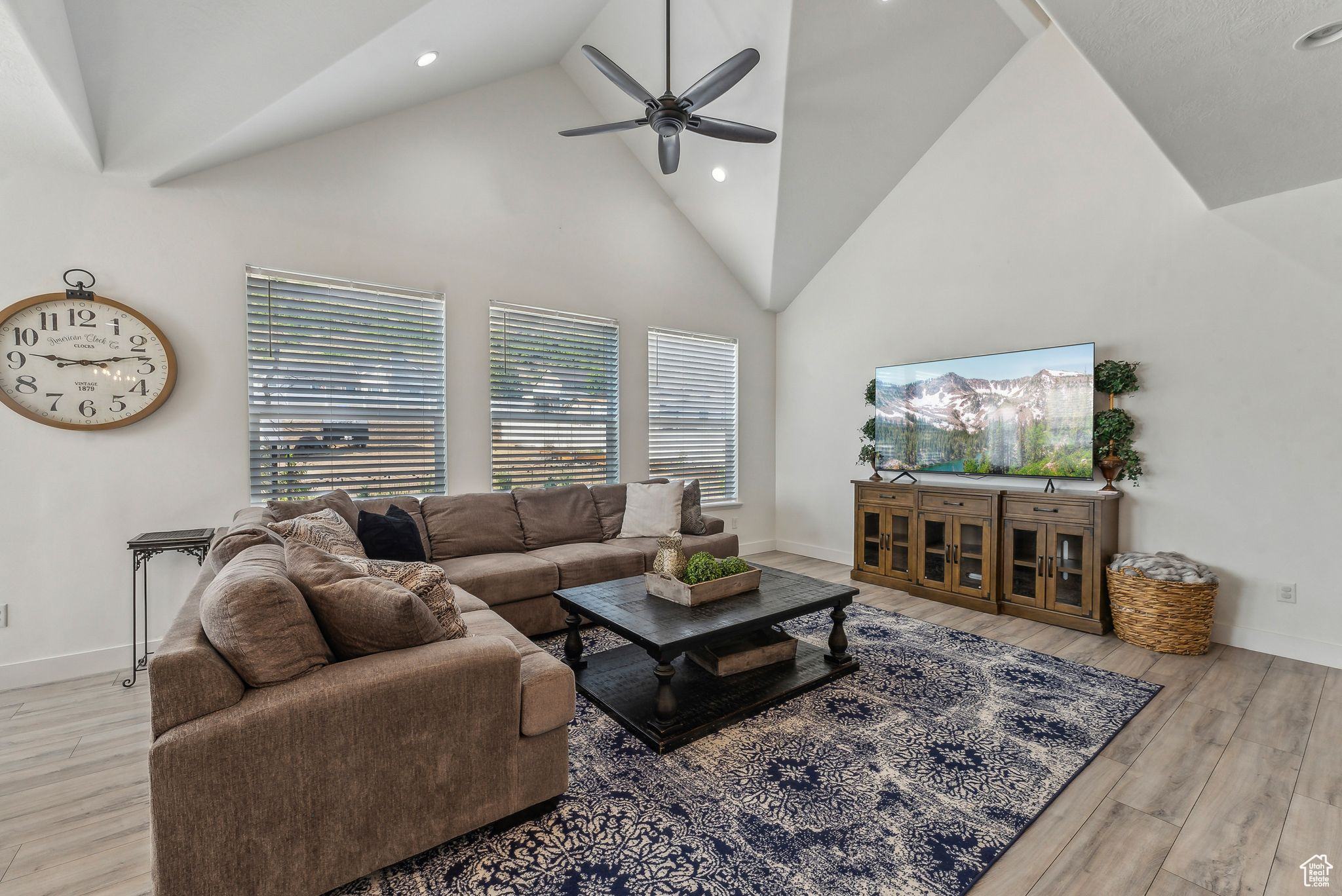 Living room with high vaulted ceiling, ceiling fan, and light wood-type flooring