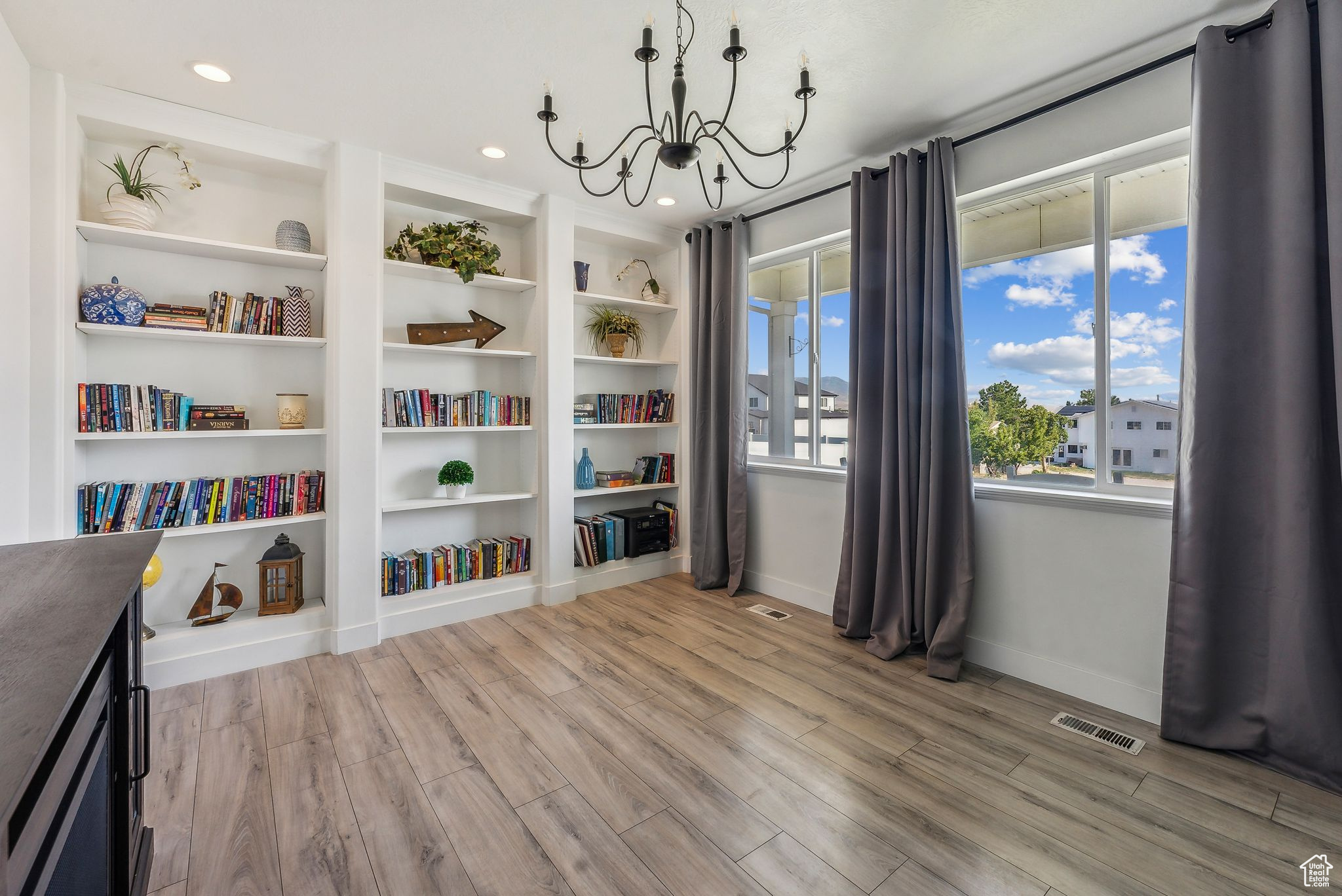 Sitting room with built in shelves, an inviting chandelier, and light wood-type flooring