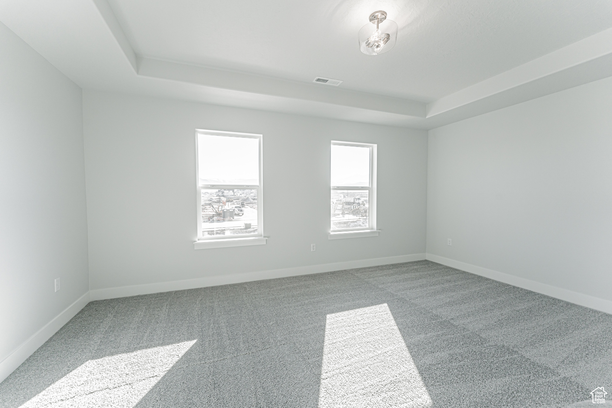 Carpeted empty room featuring a tray ceiling