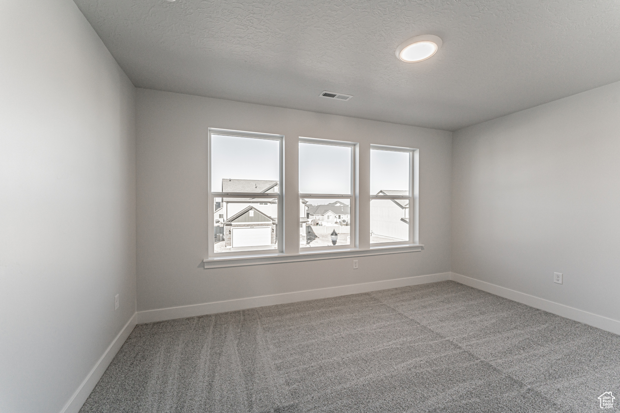 Unfurnished room with light carpet and a textured ceiling